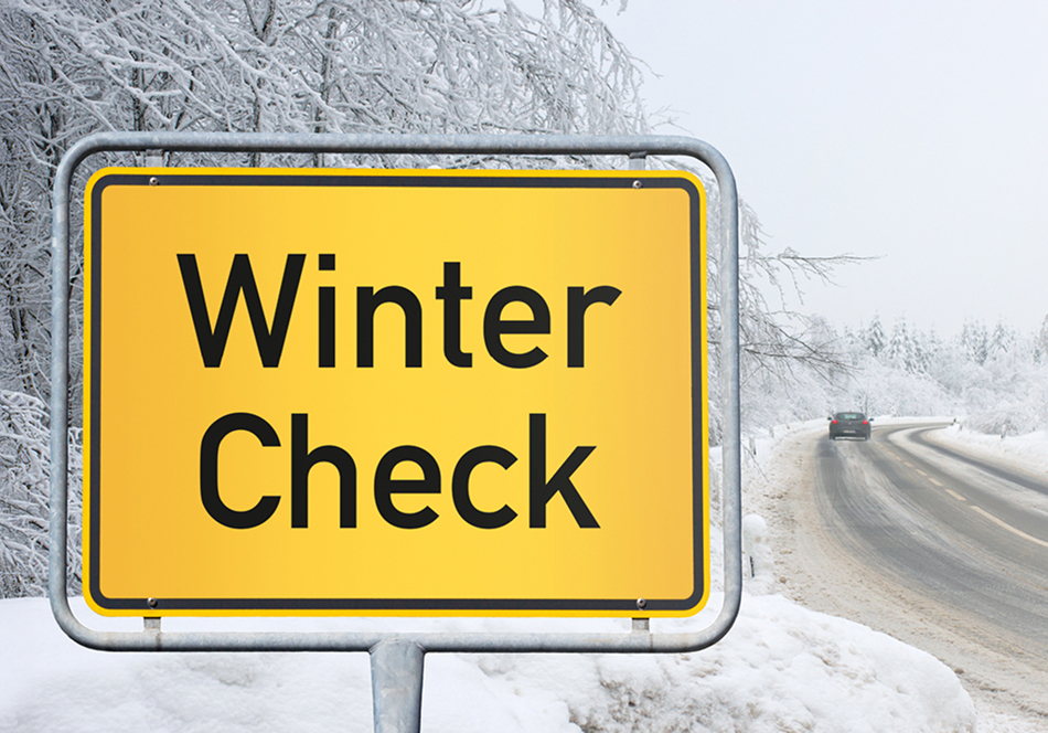 Winter-Check Ein Ortschild mit der Aufschrift Winter-Check in verschneiter Landschaft